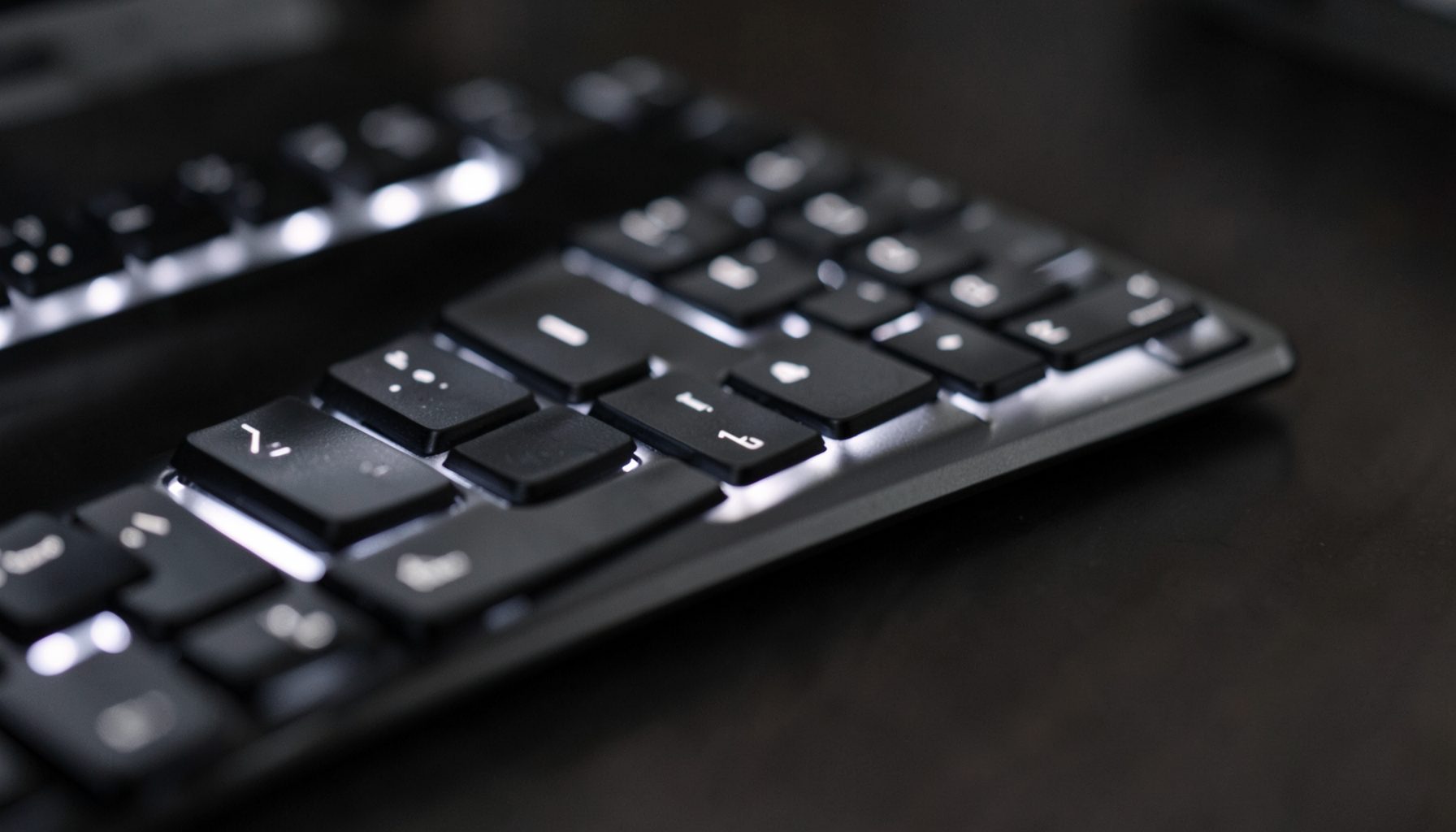 Close-up of a wireless keyboard with soft backlighting, dark metallic tones